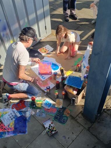 Künstlerin und Kind arbeiten gemeinsam an einem Kunstwerk