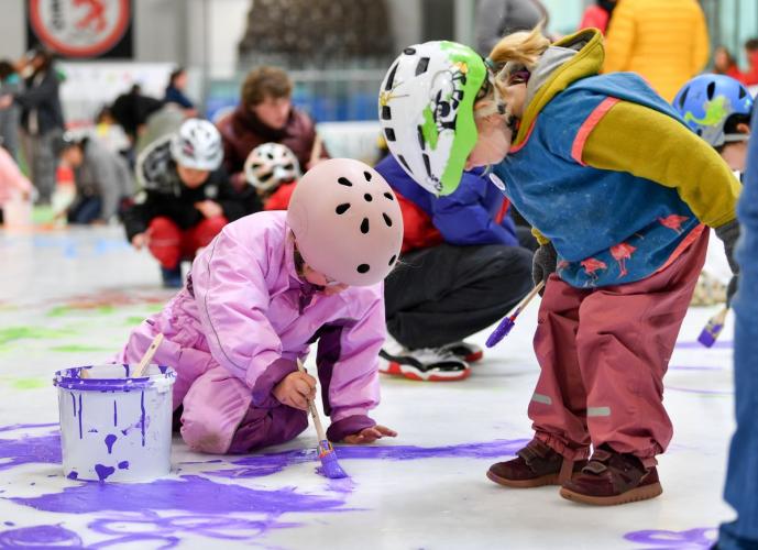 Kinder malen mit lila Farbe auf dem Eis