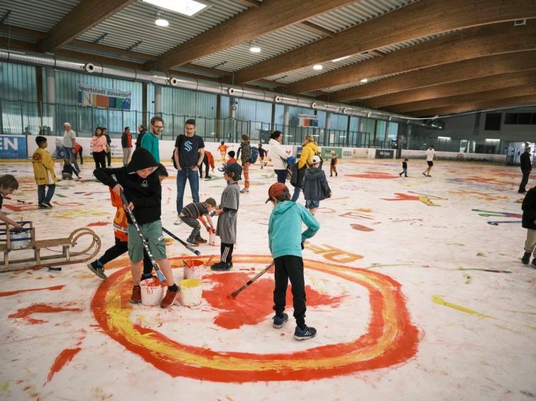 Kinder und Erwachsene malen gemeinsam auf dem Eis mit bunten Farben